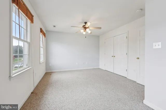 an empty room with windows and ceiling fan