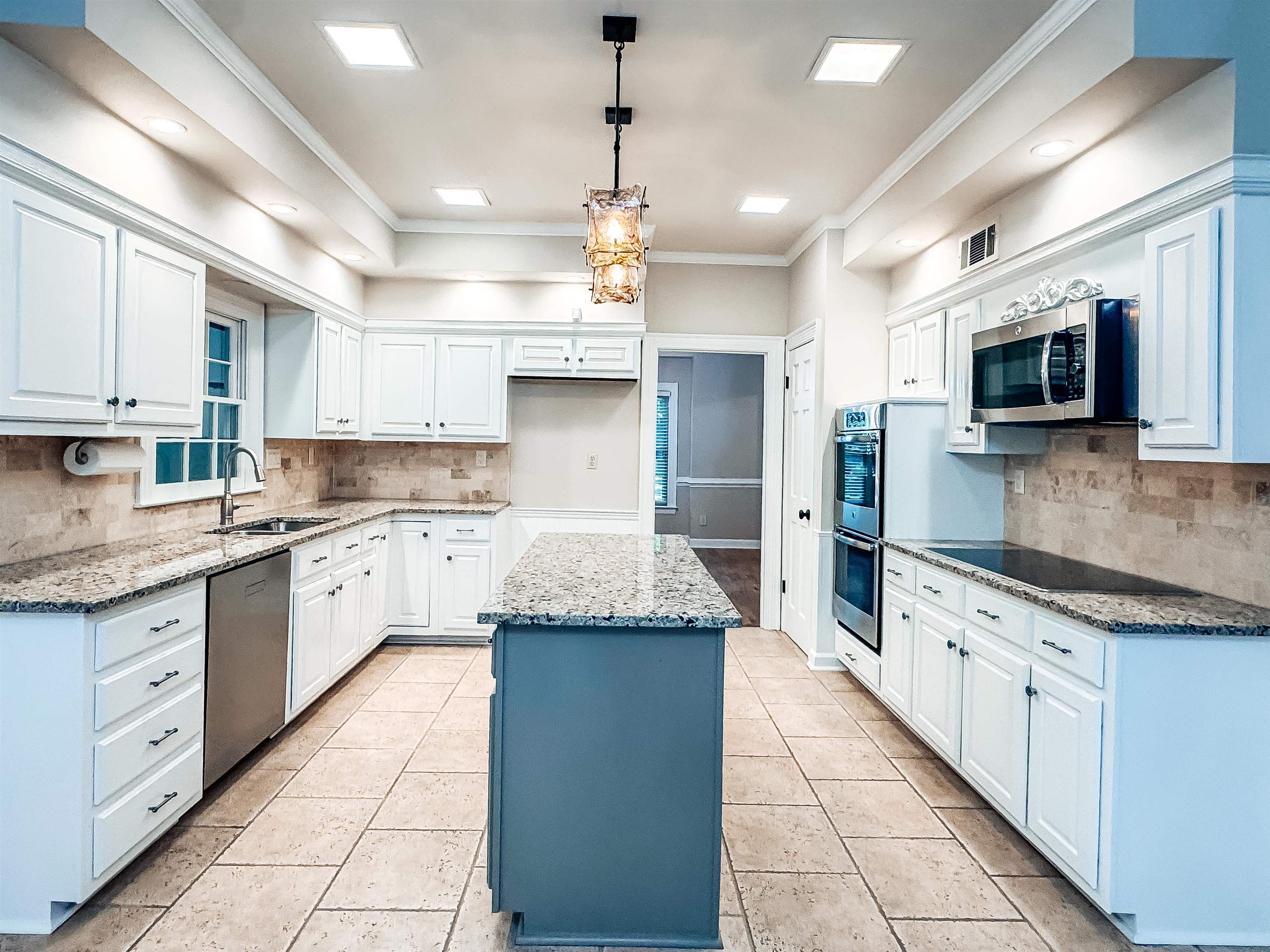 832 South Tree Drive Collierville, TN 38017 - Photo 12 of 40 Spacious kitchen featuring white cabinetry, light-toned stone countertops, and a central island with a contrasting base