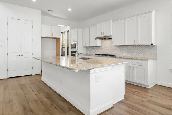 a kitchen with kitchen island white cabinets and stainless steel appliances