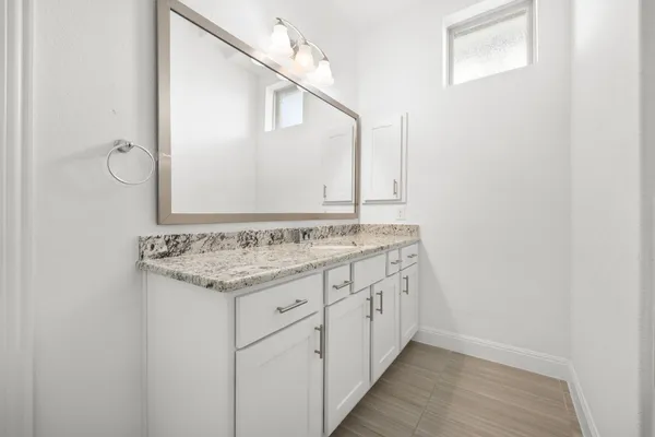 a bathroom with a granite countertop sink and a mirror