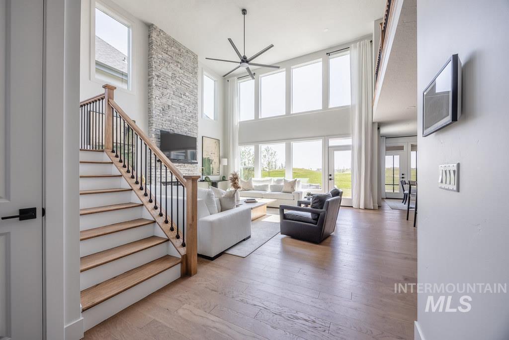 7385 West Flathead Lk Street Eagle, ID 83616 - Photo 7 of 14 Living room with light wood finished floors, stairway, ceiling fan, healthy amount of natural light, and a towering ceiling