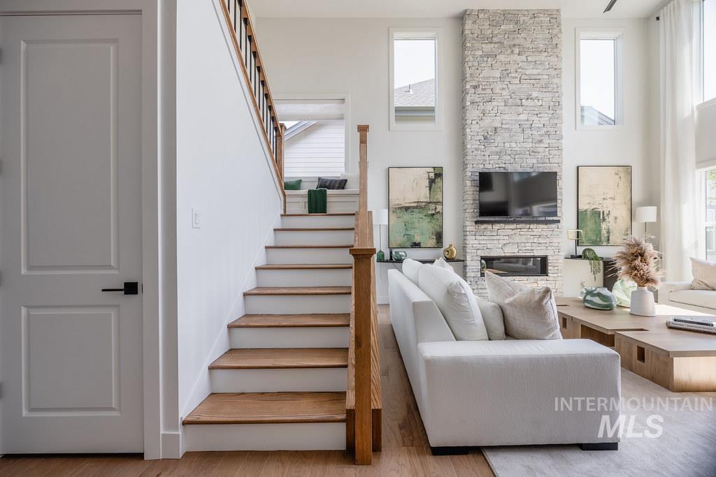 7385 West Flathead Lk Street Eagle, ID 83616 - Photo 8 of 14 Living room featuring light wood-style floors, a stone fireplace, and stairs