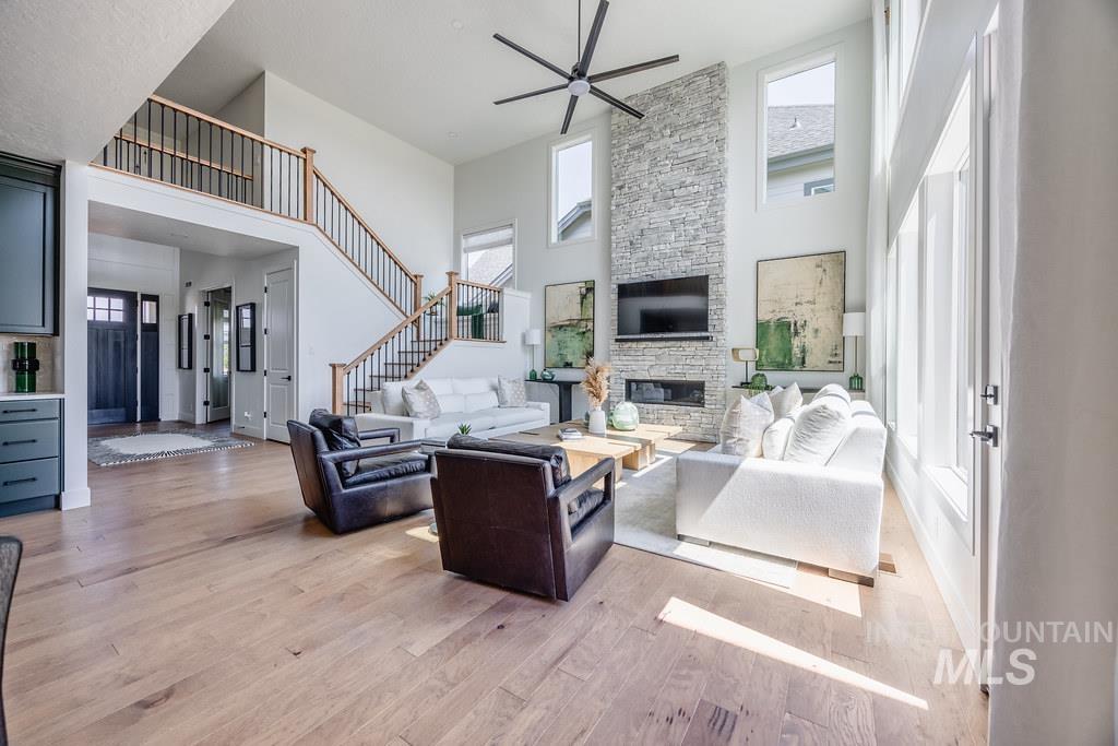 7385 West Flathead Lk Street Eagle, ID 83616 - Photo 10 of 14 Living area featuring a high ceiling, light wood-style floors, ceiling fan, stairs, and a fireplace