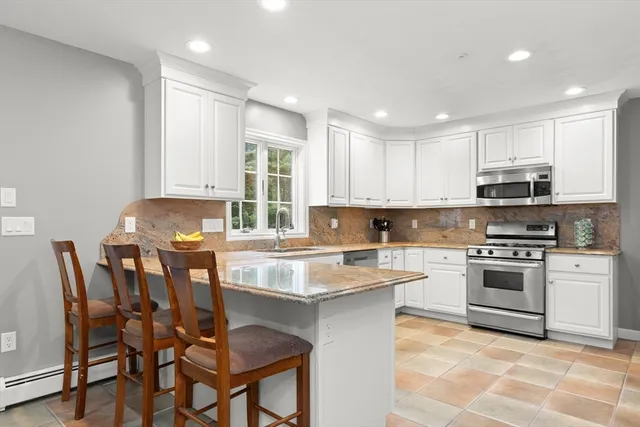 a kitchen with stainless steel appliances granite countertop a stove top oven a sink dishwasher and white cabinets with wooden floor