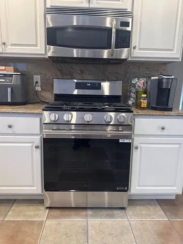 a stove top oven sitting inside of a kitchen and white cabinets