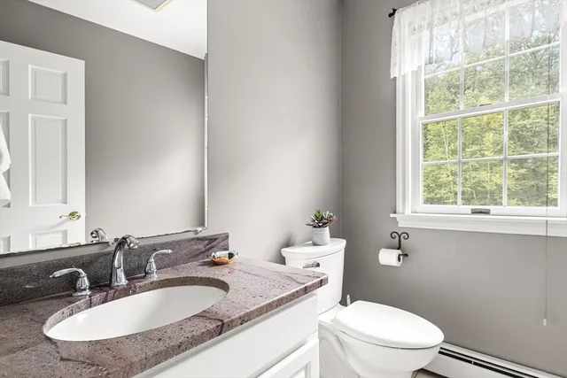 a bathroom with a granite countertop toilet a sink and a mirror