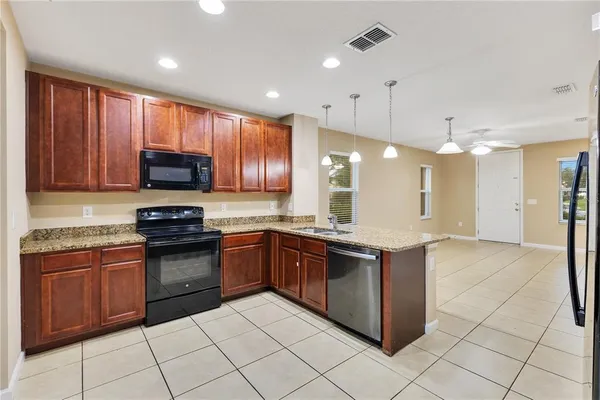 a large kitchen with stainless steel appliances granite countertop a stove sink and cabinets