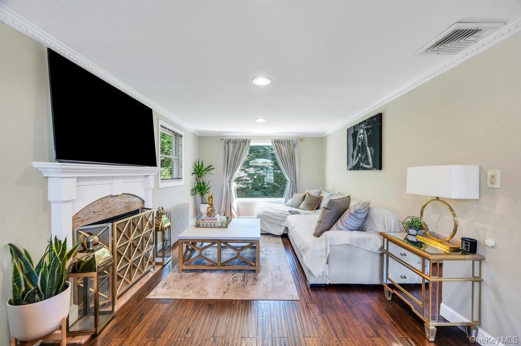 357 Wynsum Avenue Merrick, NY 11566 - Photo 11 of 40 a living room with furniture a flat screen tv and a fireplace