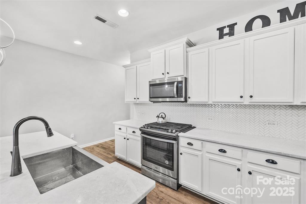 1117 Streamside Lane York, SC 29745 - Photo 6 of 21 a kitchen with white cabinets a sink and stainless steel appliances