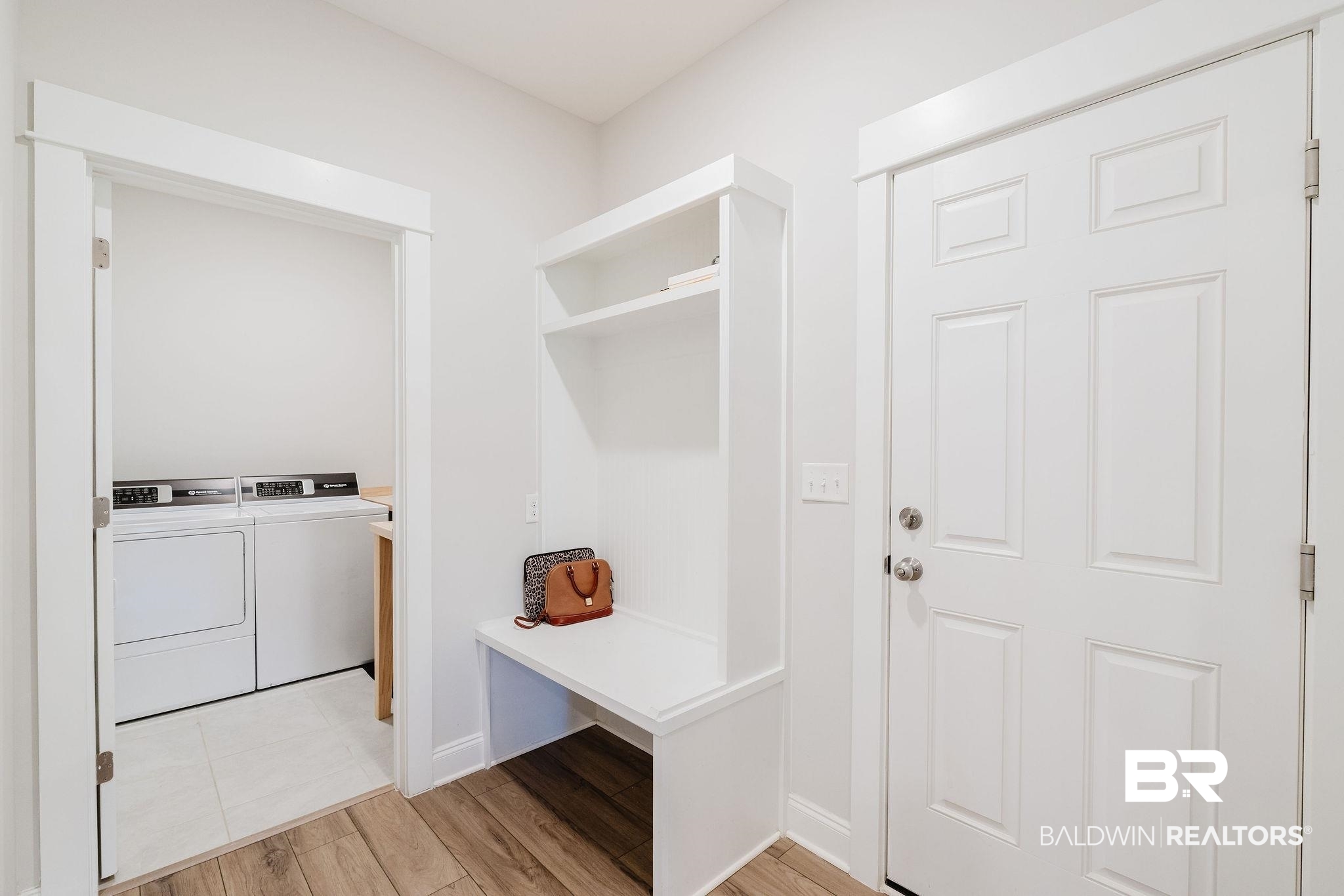 7872 Calverton Street Foley, AL 36535 - Photo 43 of 76 Entry area featuring wood-finish flooring, a white paneled door, and a built-in storage bench with shelving