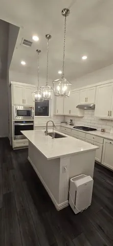 a kitchen with stainless steel appliances granite countertop a stove a refrigerator and a wooden floor