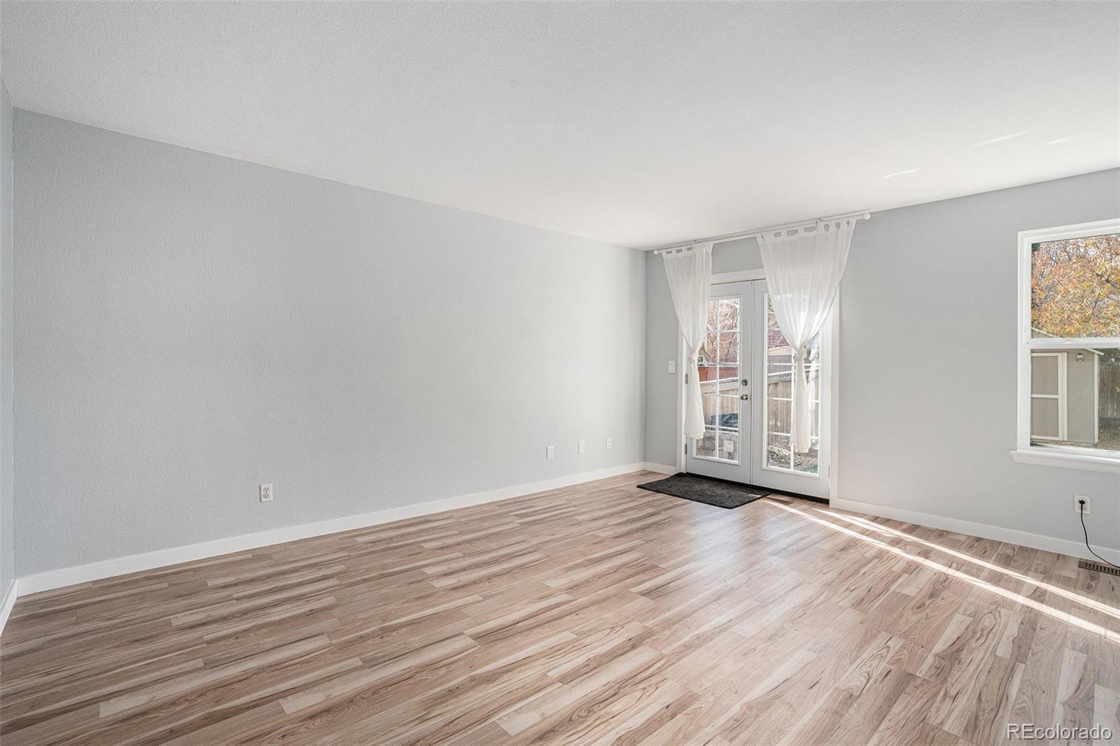 1085 Mockingbird Street Brighton, CO 80601 - Photo 7 of 21 a view of an empty room with wooden floor and a window