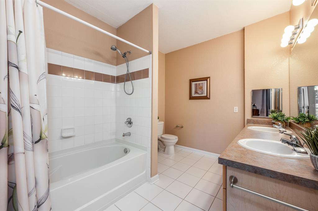 102 Terrace Ridge Circle, Unit 102 Davenport, FL 33896 - Photo 19 of 32 a bathroom with a granite countertop sink a toilet and shower