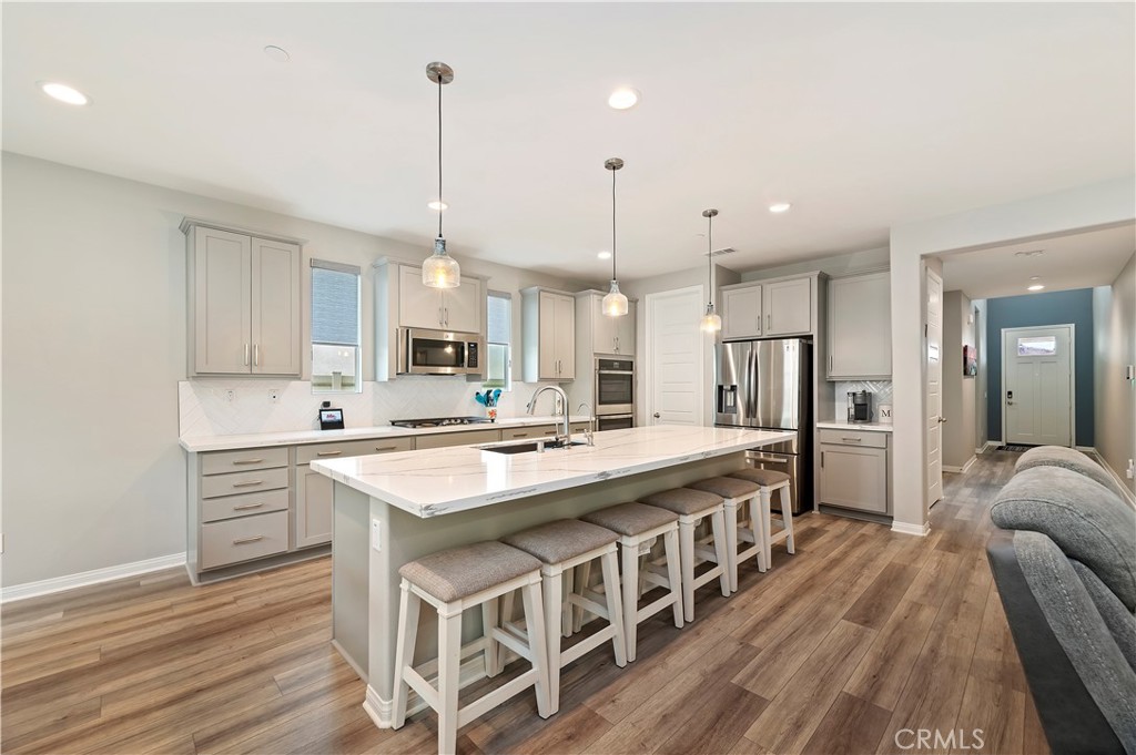 39526 Verbena Way Temecula, CA 92591 - Photo 20 of 55 a kitchen with stainless steel appliances granite countertop a kitchen island a stove a refrigerator a sink and a wooden floors