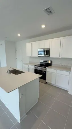 a kitchen with a sink a stove top oven and cabinets