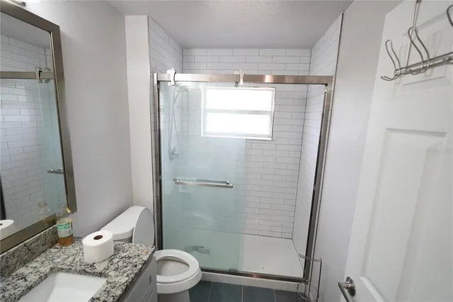 a bathroom with a granite countertop shower a toilet and a sink