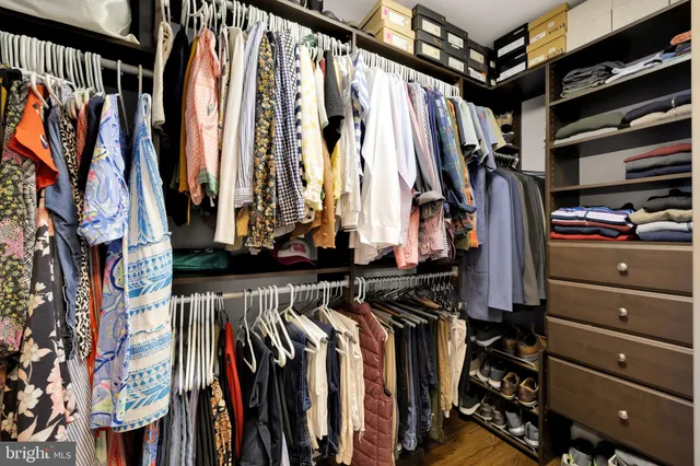 a view of walk in closet with clothes and shoes