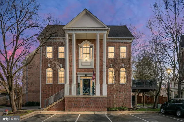 a front view of a building with lot of cars and trees