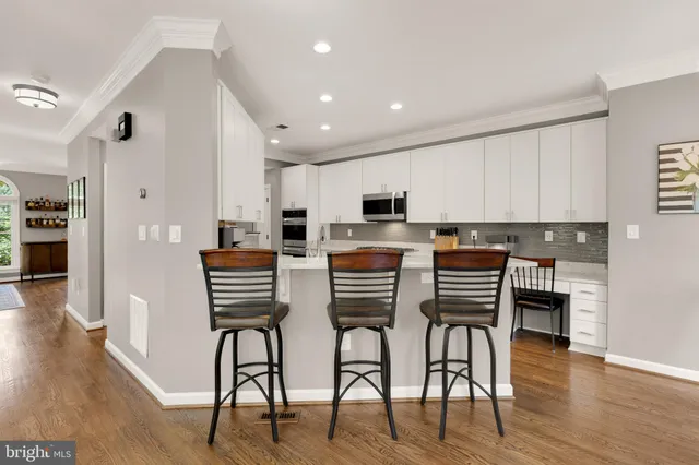 a kitchen with stainless steel appliances kitchen island granite countertop a table chairs and a refrigerator