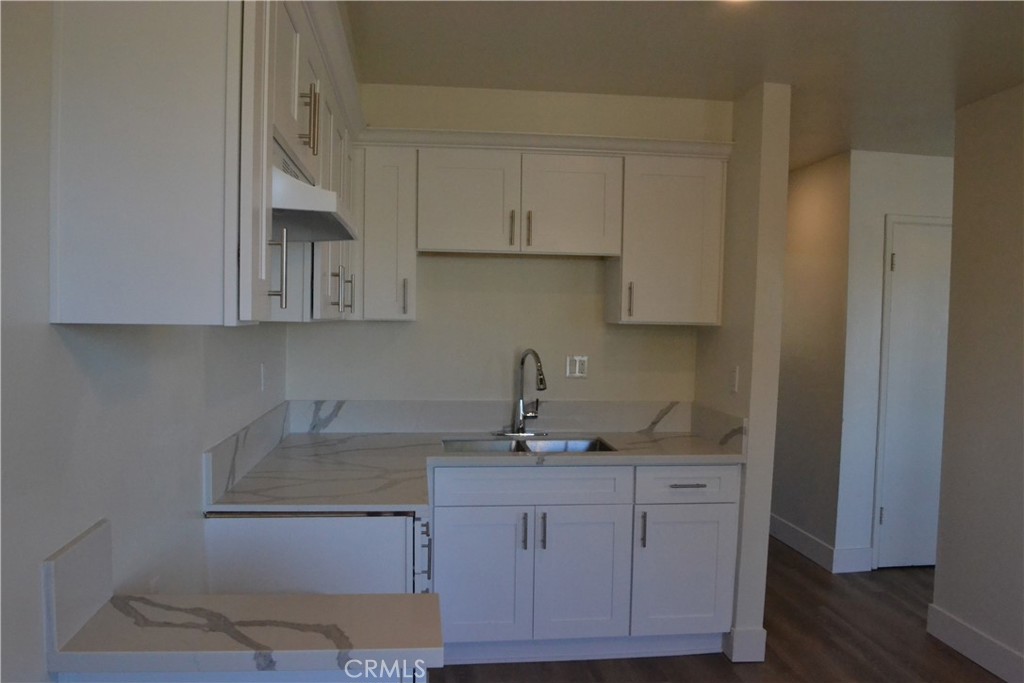 a kitchen with granite countertop white cabinets and a sink