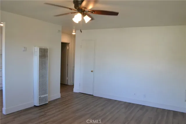 an empty room with wooden floor fan and windows