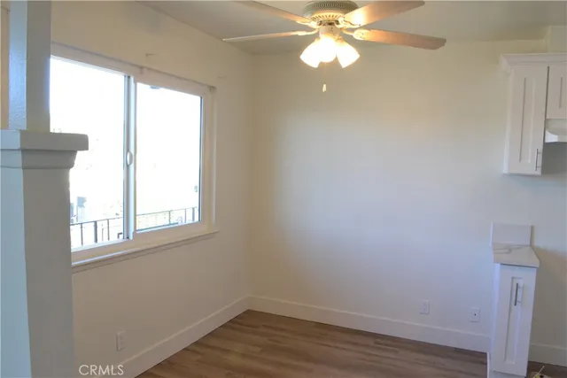 an empty room with wooden floor windows and fan
