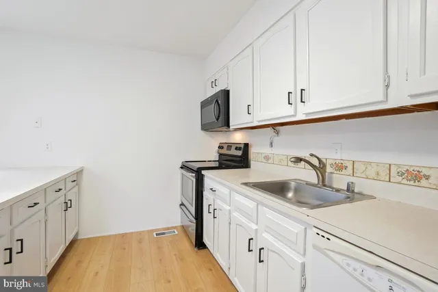 a kitchen with white cabinets a sink and dishwasher