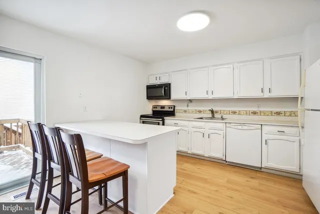 a kitchen with stainless steel appliances granite countertop a stove top oven a sink a dining table and chairs with wooden floor