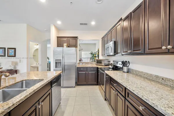 a kitchen with granite countertop stainless steel appliances cabinets a sink and a counter top space