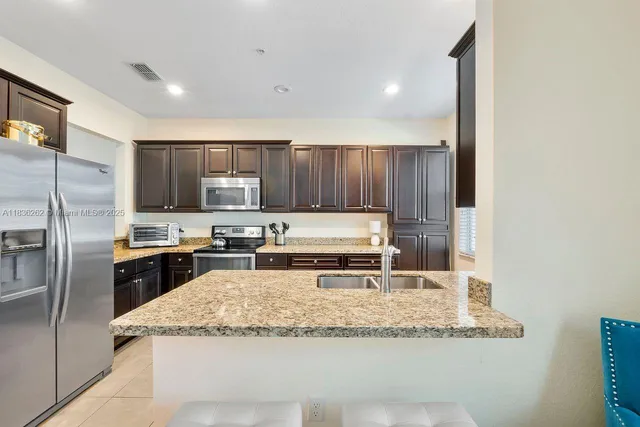 a kitchen with granite countertop wooden cabinets a refrigerator and a sink