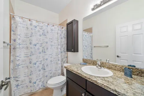 a bathroom with a granite countertop sink toilet and shower