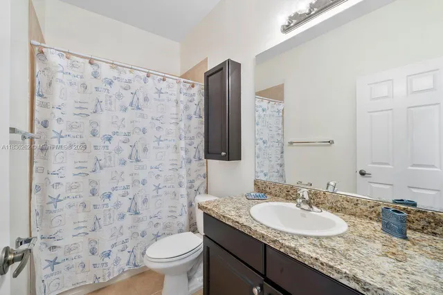 a bathroom with a granite countertop sink toilet and shower