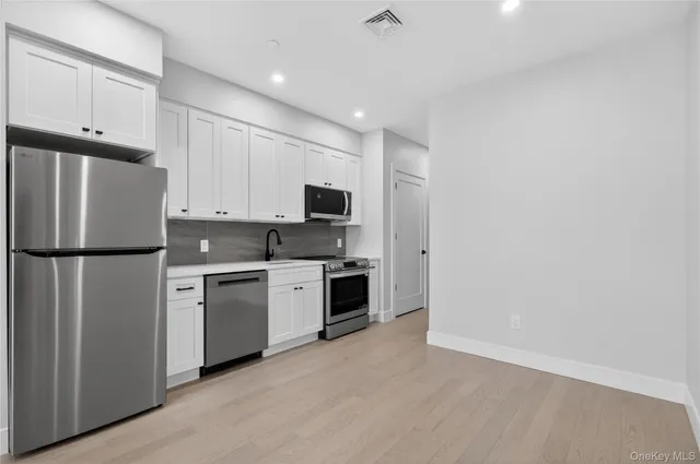 a kitchen with white cabinets and stainless steel appliances