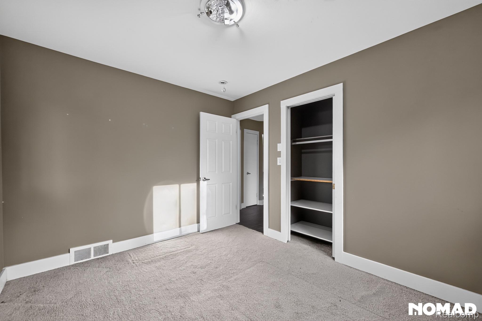 8315 Hilton Road Brighton, MI 48114 - Photo 10 of 26 Carpeted room featuring a white interior door, a built-in closet with shelving and hanging rods, and a ceiling-mounted light fixture