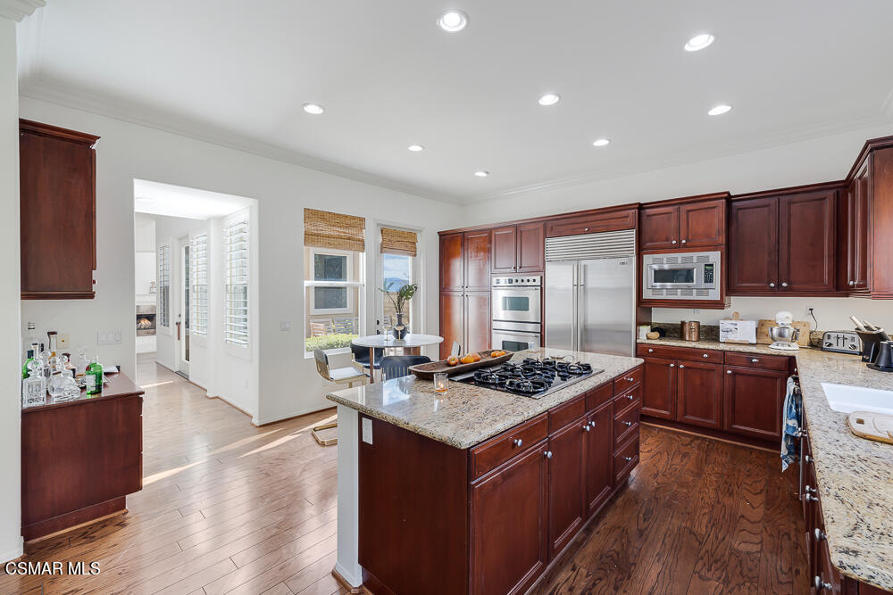 6103 Deerhill Road Oak Park, CA 91377 - Photo 12 of 40 a kitchen with stainless steel appliances granite countertop a stove a sink dishwasher and a refrigerator with wooden cabinets