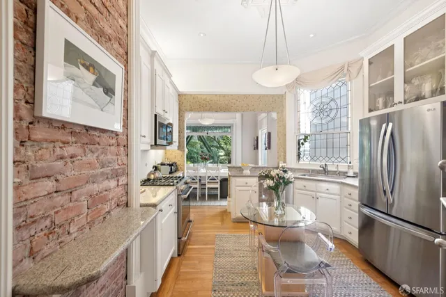 a dining room with stainless steel appliances a large window and wooden floor