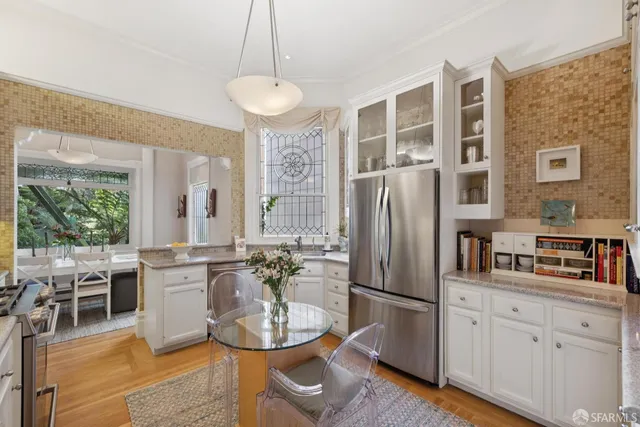 a kitchen with stainless steel appliances granite countertop a refrigerator a stove a sink dishwasher a dining table and chairs with wooden floor