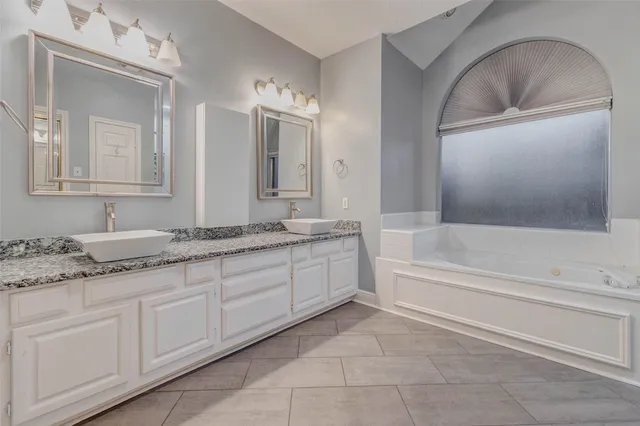 a bathroom with a granite countertop sink a mirror and bathtub