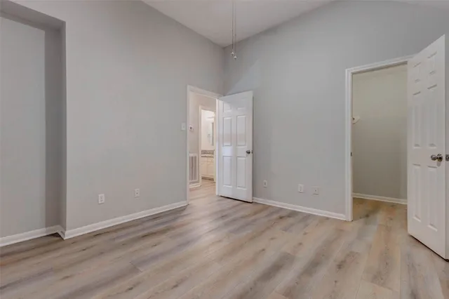 a view of an empty room with wooden floor and closet