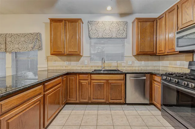 a kitchen with stainless steel appliances granite countertop a sink stove and cabinets