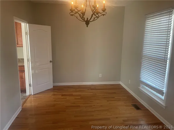 an empty room with chandelier fan and windows