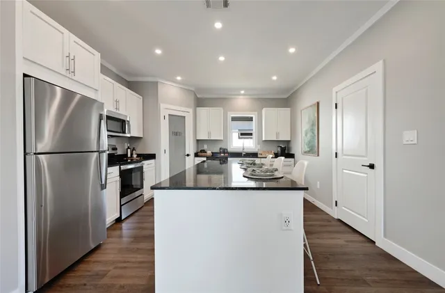 a kitchen with kitchen island white cabinets and stainless steel appliances