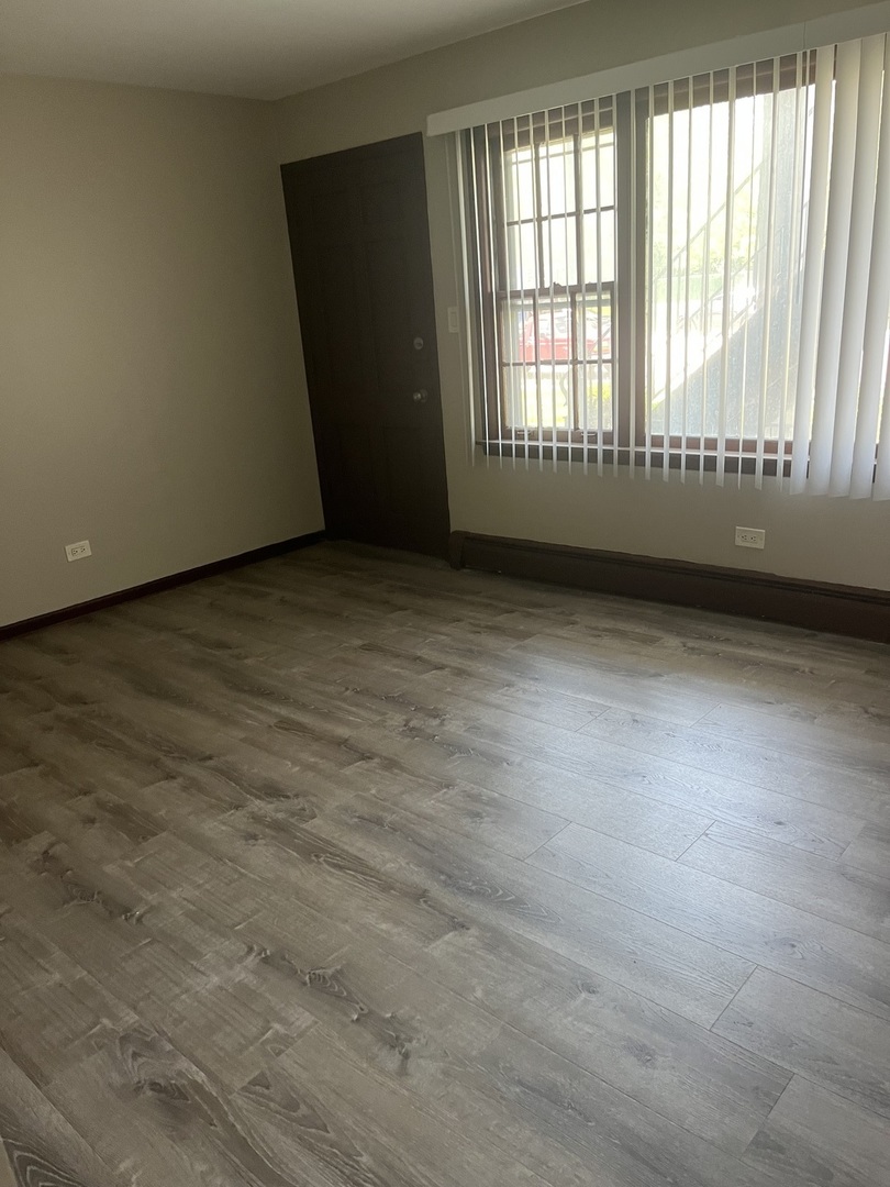 7831 Roberts Road, Unit 3 Bridgeview, IL 60455 - Photo 2 of 7 an empty room with wooden floor and windows