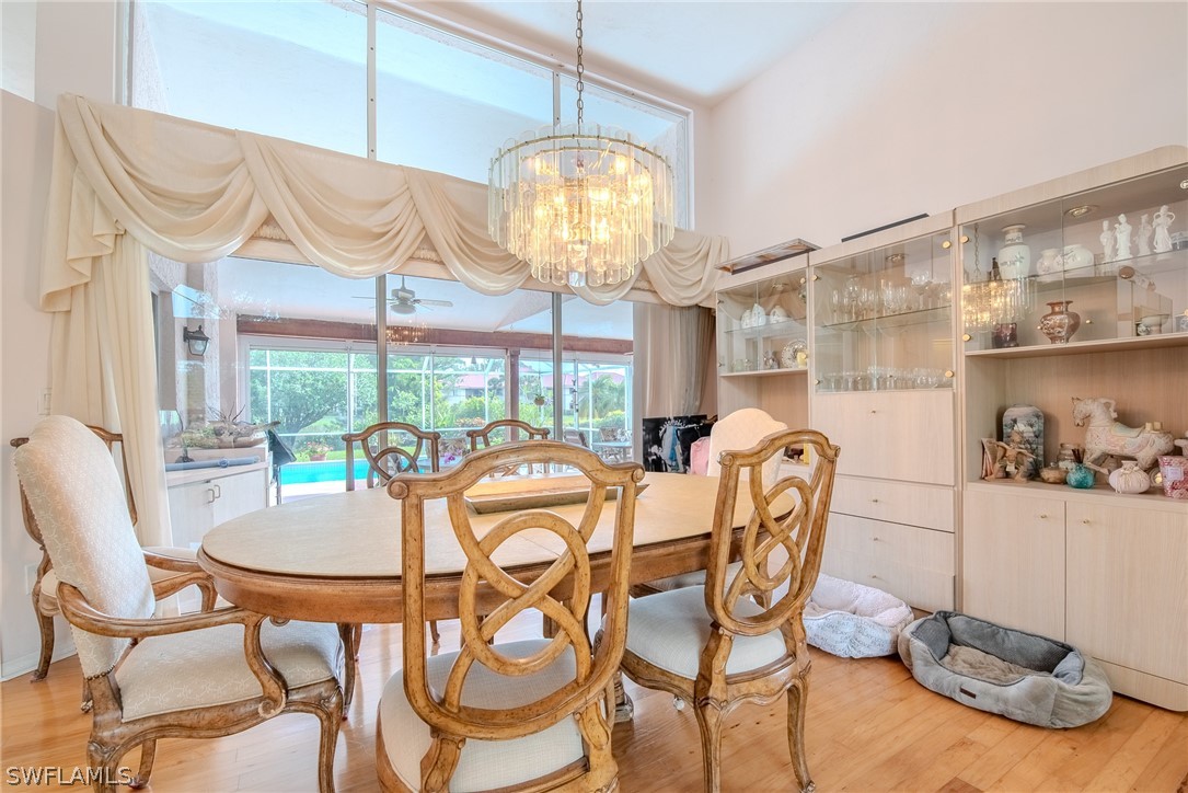 7181 Appleby Drive Naples, FL 34104 - Photo 12 of 29 a dining room with furniture a chandelier and wooden floor