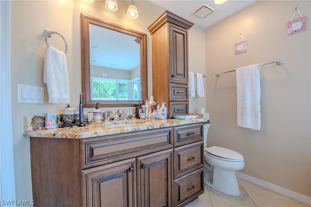 7181 Appleby Drive Naples, FL 34104 - Photo 18 of 29 a bathroom with a granite countertop sink a toilet and a mirror