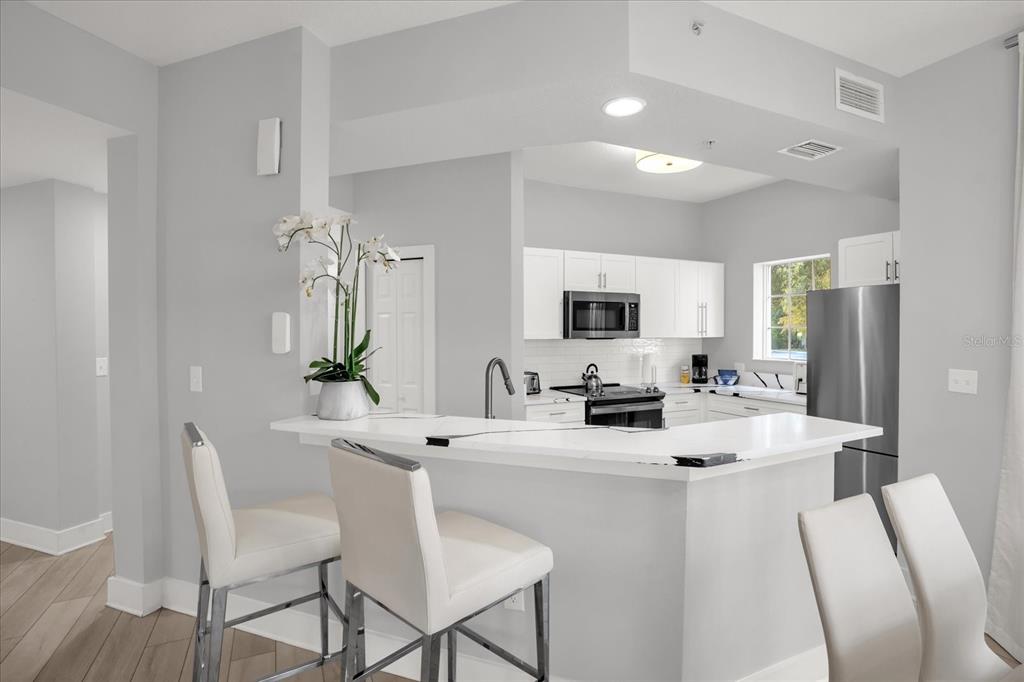 8774 Worldquest Boulevard Orlando, FL 32821 - Photo 5 of 35 a kitchen with stainless steel appliances kitchen island granite countertop a dining table chairs and a refrigerator