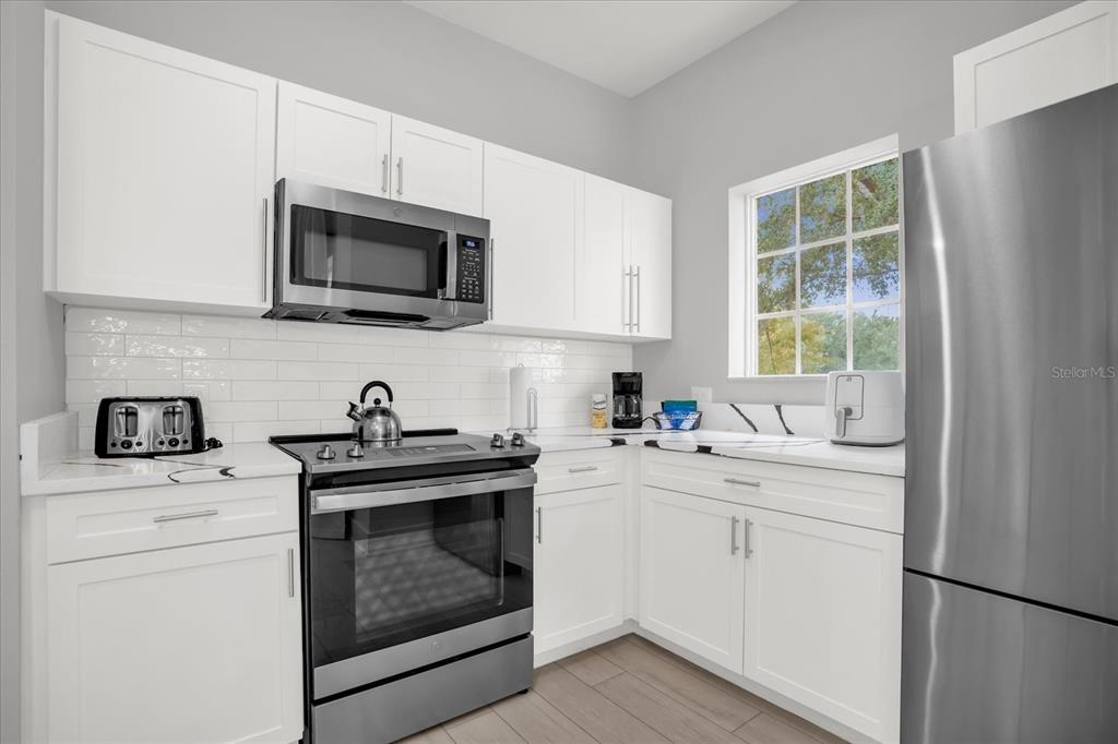 8774 Worldquest Boulevard Orlando, FL 32821 - Photo 10 of 35 a kitchen with white cabinets stainless steel appliances and sink