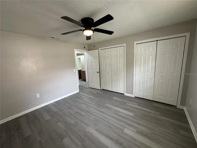 an empty room with wooden floor chandelier fan and windows