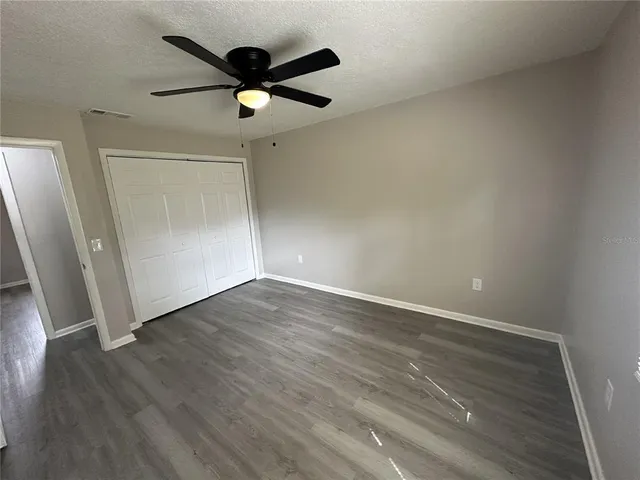 an empty room with wooden floor and a ceiling fan