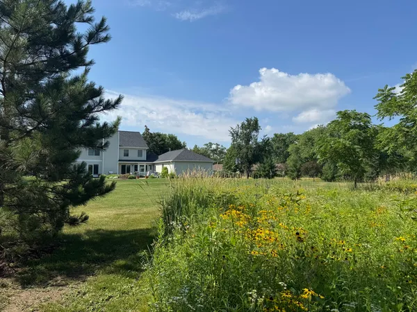 a view of white house with a big yard and large trees
